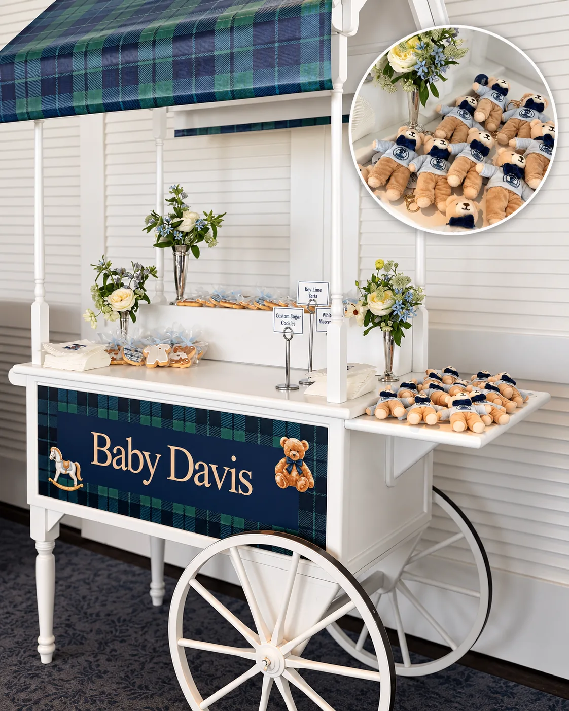 Personalized plush teddy bear bag charms with light blue sweaters displayed on a white vintage cart with a plaid awning at a baby shower